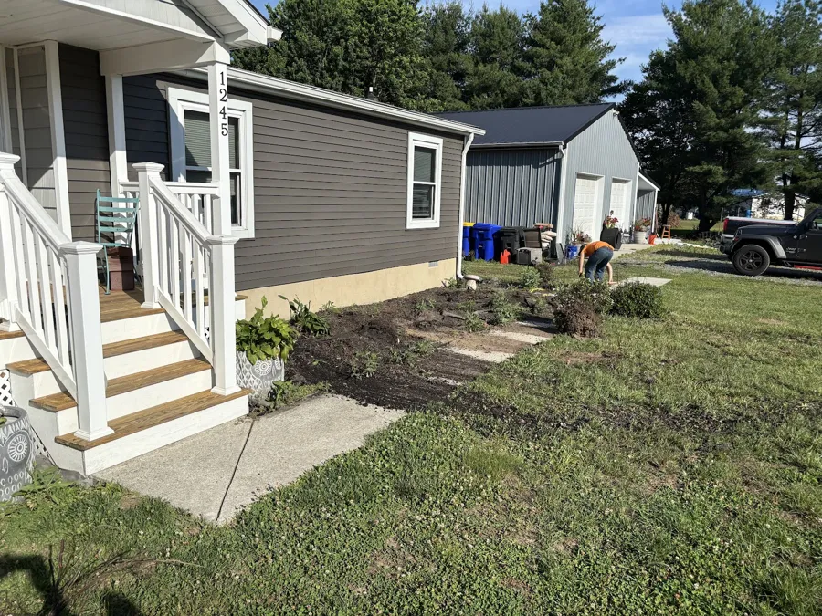 Front bed being cleared and reshaped along the porch of a house